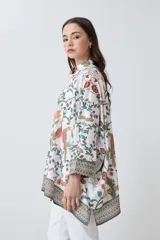 Camisa oversized con estampa floral en tonos naranja, verde y rojo sobre fondo blanco, con cuello clásico y cierre frontal con botones.