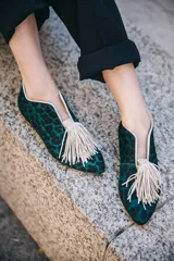 Botines bajos con estampado animal print en tonos verde y negro, con escote en V y borlas decorativas en el empeine.