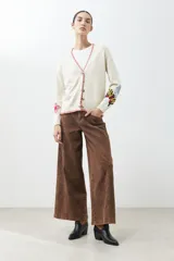 Cárdigan color crema con botones, ribete rojo y bordados de flores y mariposas en las mangas.