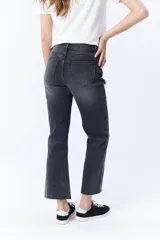 Pantalón de jean negro con corte cropped y flare, de tiro alto y con terminación desflecada.