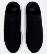 Championes negros de tela tejida, estilo slip-on, con suela blanca y detalles geométricos en los laterales.