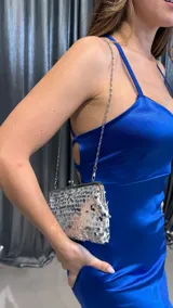 Cartera de mano plateada cubierta de lentejuelas, con cierre metálico y cadena plateada fina para colgar al hombro.