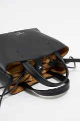 Bolso tote pequeño color visón de piel granulada con doble asa corta y correa bandolera ajustable y extraíble. Incluye bolsa interior ajustable con cordones. Logotipo de la marca grabado en el frente.
