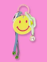 Llavero con aro rosado, dije de cara sonriente amarilla, cadena de eslabones verde agua y colgante de perla.