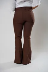 Pantalón marrón de tiro alto con cierre frontal de cremallera y botón. Tiene bolsillos delanteros y traseros, y corte acampanado.