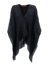 Capa o poncho de tejido de punto negro con patrón de zigzag y detalles brillantes o lentejuelas incrustadas. Presenta un escote en V cruzado y bordes deshilachados.