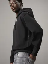 Buzo negro de poliéster con capucha y cordones ajustables, puños y dobladillo con punto canalé, corte relaxed y cintas decorativas con el logo de Calvin Klein repetido en las mangas.