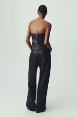 Pantalón marrón de tiro medio con trabillas en la cintura, cinco bolsillos y pernera ancha. Cierre frontal con cremallera, botón oculto y gancho metálico.