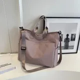 Bolso tipo tote color celeste con correa larga verde y asas cortas.
