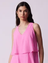 Vestido corto de gasa color fucsia, con escote en V y capas superpuestas. Incluye forro interno a tono.
