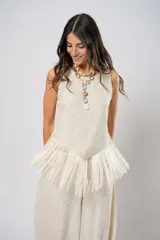 Blusa beige de lino bordado, sin mangas y con terminación en flecos.