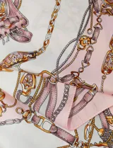 Pañuelo cuadrado de satén con estampado de cadenas doradas y detalles en rosa y blanco.