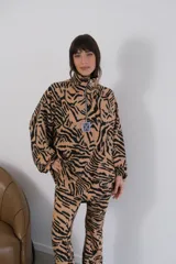 Buzo de morley con estampado animal print tipo cebra en tonos beige y negro, con cuello alto y cierre parcial con cremallera.