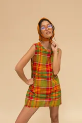 Vestido corto sin mangas con estampado de cuadros en tonos azul, rojo, verde y blanco. Tiene cuello redondo y ruedo con flecos.