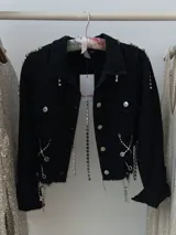 Campera cropped de jean negra con tiras de strass plateado y botones plateados al frente.
