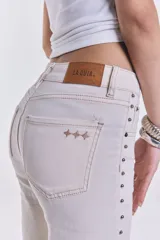 Pantalón jean color crudo, de corte recto y tiro medio, con tachas plateadas en los laterales. Sin lycra.