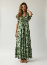 Vestido largo de poliéster con estampado floral en tonos verdes y blancos, corte amplio, mangas cortas con volados, escote en V con lazo ajustable y falda con volados en el ruedo.