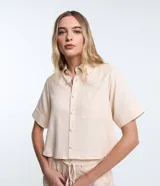 Camisa color beige claro, corta, con cuello inglés, manga corta, bolsillo en el pecho y abotonada adelante.