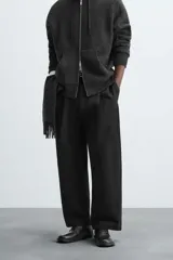 Pantalón negro de corte ancho, con pinzas en la cintura, bolsillos laterales y traseros de ojal.
