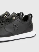 Zapatillas deportivas Tommy Hilfiger negras de cuero sintético, con cordones y suela blanca.