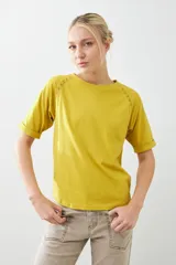 Remera color verde pistacho, de corte recto y manga corta raglán con detalle de vainillas en los hombros.