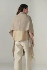 Chal de lana fina sin teñir, con calce en hombros, abrochadura con alamar de fieltro, bolsillos de cuero y terminación con flecos. Diseño exclusivo de Don Baez, hecho en Uruguay.