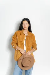 Camisa color ocre de gamuza, con cuello clásico, mangas largas con puños abotonados, cierre frontal con botones a presión y bolsillo de parche en el pecho.