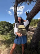 Mochila urbana de diseño compacto, color violeta/malva, con acabado ligeramente brillante. Presenta un compartimento principal con doble cierre superior y bolsillos laterales con cierre.