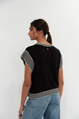 Top negro de tejido de punto con cuello redondo y mangas cortas con ribete blanco.