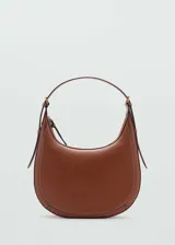 Bolso de hombro tipo hobo con diseño de media luna, confeccionado en material efecto piel color marrón. Cuenta con cierre de cremallera, asa ajustable con hebillas laterales y costuras decorativas en contraste.