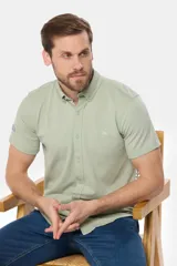 Camisa celeste de piqué con manga corta, botones personalizados y logo bordado a tono.