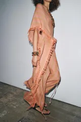 Vestido largo tipo kaftán confeccionado en lino a rayas verticales en tonos naranja y verde. Tiene cuello redondo con escote en V, mangas cortas amplias, acabado deshilachado y cinturón de cordón en el mismo tejido.