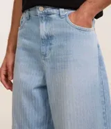 Pantalón de jeans celeste con textura, corte super baggy, cintura con trabillas, cierre tradicional y bolsillos.
