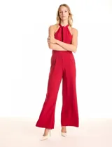 Enterito largo de crepe color rojo, con escote halter anudado y pierna ancha. Presenta bolsillos delanteros y abertura en la espalda con cierre invisible y botón.
