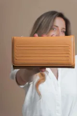 Billetera larga color mostaza de símil cuero con tapa y repartición con cierre. Compartimento con tarjeteros y bolsillos. Compartimento posterior incluye monedero con cierre, tarjeteros y billetes. Bolsillo atrás con cierre.
