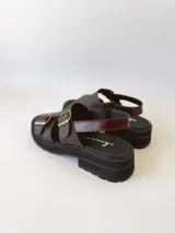 Sandalias de cuero color chocolate con plataforma track negra y hebillas metálicas plateadas.