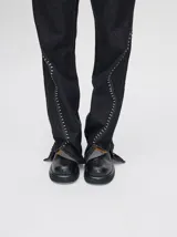 Pantalón de jean azul de tiro alto y corte oxford con apliques metálicos en bolsillos y laterales.