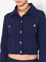 Saco azul tejido en hilado frío con punto cerrado y estructura pesada. Tiene acceso frontal con botones dorados y mangas largas.