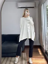 Maxisweater color crudo, de tejido símil bremer, talle único (abarca hasta 2xl). Presenta detalles en las mangas, aperturas laterales y es más largo en la parte trasera.