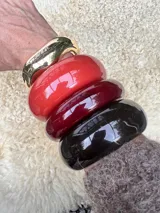 Set de pulseras rígidas de diferentes colores y materiales: una dorada, una roja, una bordó y una negra.