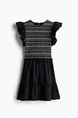 Vestido corto negro con cuerpo superior de tejido a rayas horizontales en blanco y negro, falda de popelina con volados y mangas cortas con volados.
