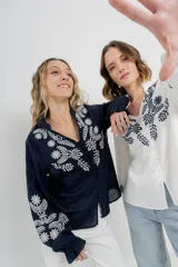 Camisa de manga larga en algodón liviano, color azul marino, con bordados florales en contraste en el frente y mangas. Cuello mao con terminación en ondas y puños fruncidos.
