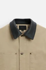 Parka negra de algodón con cuello solapa de cuero sintético, corte recto, acolchada, con bolsillos de parche y cierre frontal con botones.