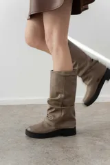 Bota alta color beige con efecto arrugado, suela track color negro y caña alta.