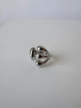 Anillo plateado de acero quirúrgico hipoalergénico con diseño abierto y tres gotas en un extremo y una gota en el otro.