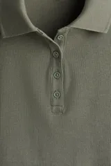 Remera polo verde oliva en punto de algodón acanalado, de manga corta con cuello clásico y tapeta de botones. Corte entallado.