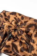 Bolso tipo bombonera con estampado animal print de leopardo en tonos marrones. Tiene cierre con cordón ajustable y asa corta para llevar al hombro.