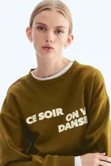 Buzo de tejido de punto color verde oliva, con cuello redondo y manga larga. Presenta un estampado frontal en blanco con texto en francés que dice "Ce soir on va danser" (Esta noche vamos a bailar).
