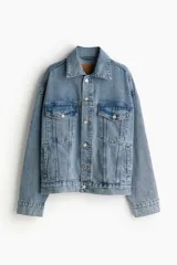 Campera de jean azul claro, corte oversized, con cuello clásico, cierre frontal con botones metálicos, bolsillos con solapa abotonada en el pecho y bolsillos laterales.