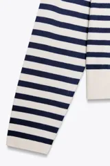 Jersey de punto color crema con rayas horizontales azul marino, de cuello redondo y manga larga.